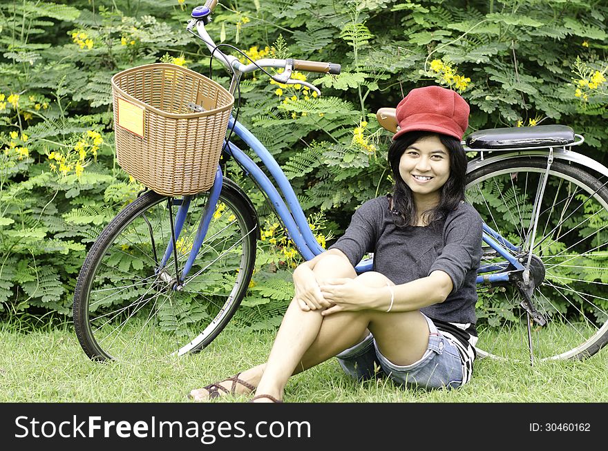 Girl With A Bicycle Rests On A Grass