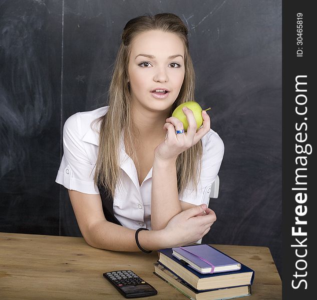 Portrait of happy cute young student near blackboard with copy book calculator pen, copy space