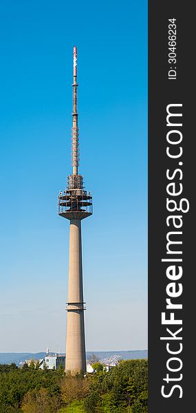 Vertical photo of a huge TV antenna tower, against blue sky. It is used for radio and TV broadcasting.