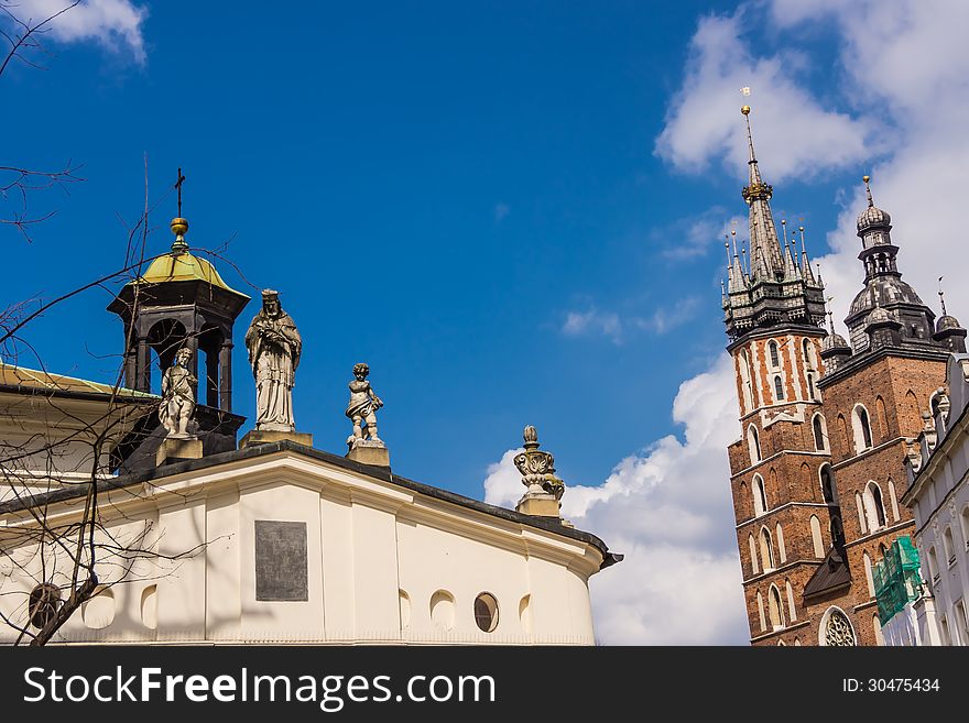 Statue of St. John Nepomuk on the roof of St. Adalbert Church on the Old Town Main Square in Krakow, Poland. On the right St.Mary’s Basilica.