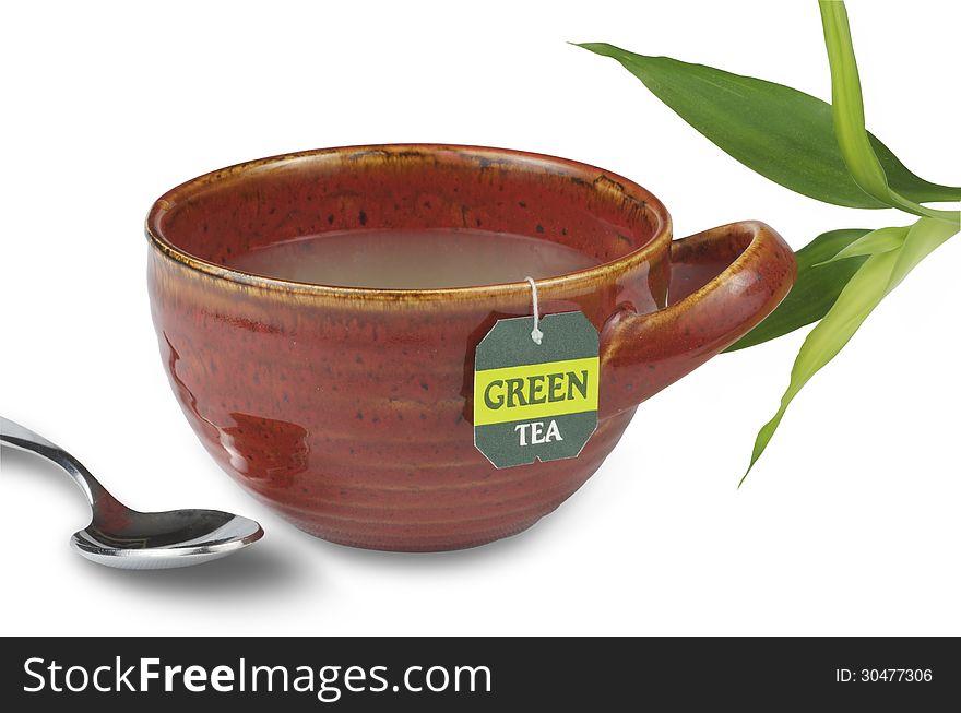 Green tea in a red tea cup pictured with bamboo and a spoon.