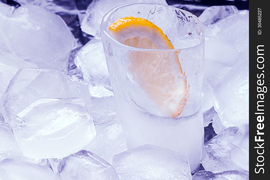 Vodka with lemon poured in a glass made of ice