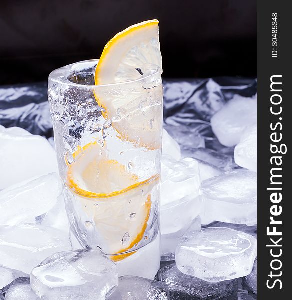 Vodka with lemon poured in a glass made of ice