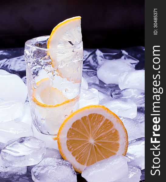 Vodka with lemon poured in a glass made of ice