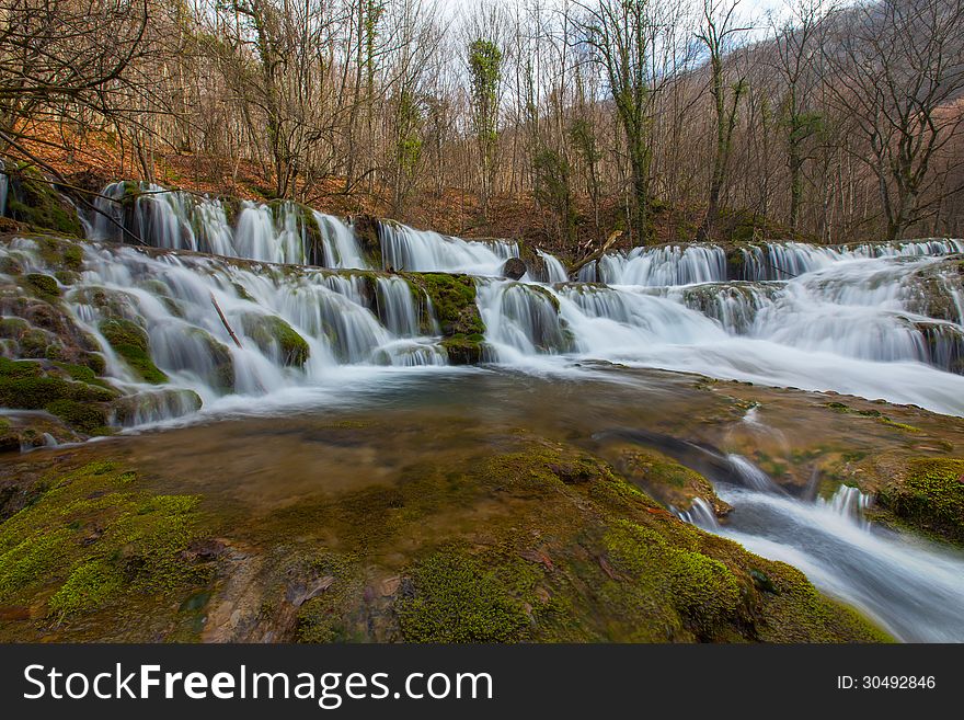 Beautiful pristine waterfalls and white water river in the mountains in early spring