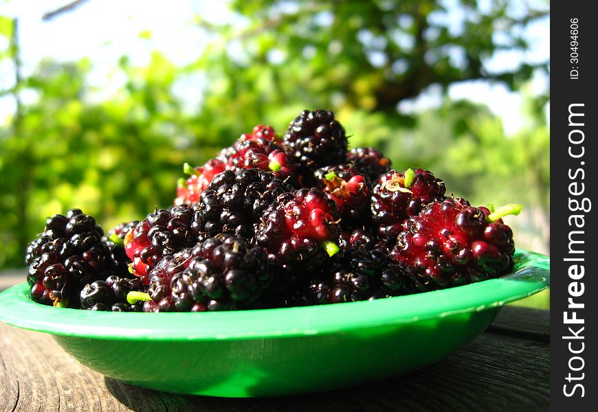 Ripe dark berries of mulberry on a plate