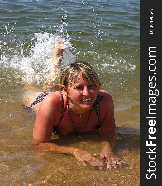 The girl splashing in the sea laying on sand