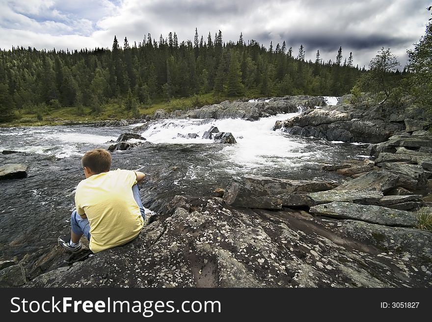 A boy sitting on a bank of a mountain river. Norway. BEAUTY OF NORWAY COLLECTION ». A boy sitting on a bank of a mountain river. Norway. BEAUTY OF NORWAY COLLECTION »