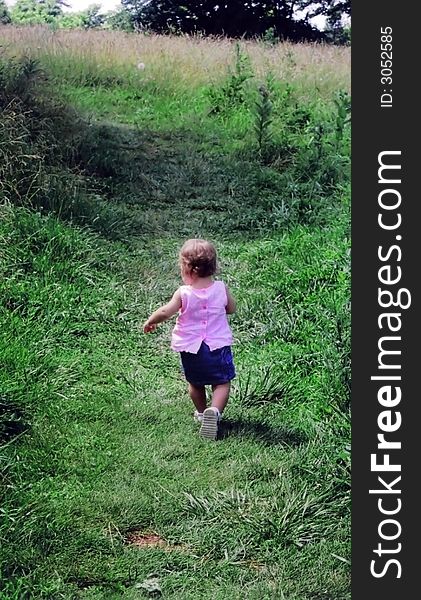 Rear view of female toddler running through countryside. Rear view of female toddler running through countryside.
