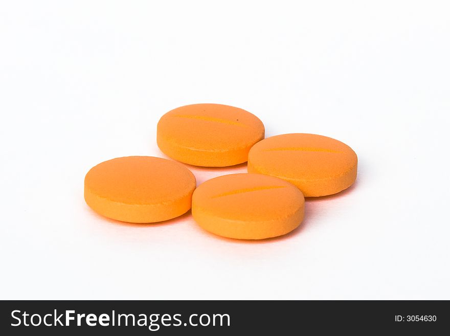 Four orange pills isolated on white background