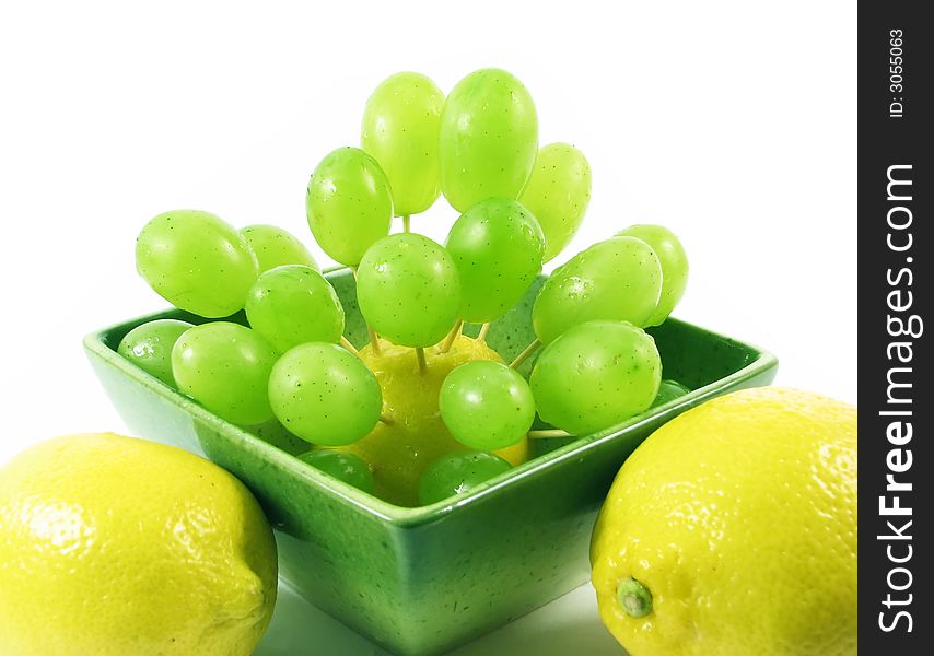 Lemon and grape in green bowl in green bowl on white background. Lemon and grape in green bowl in green bowl on white background