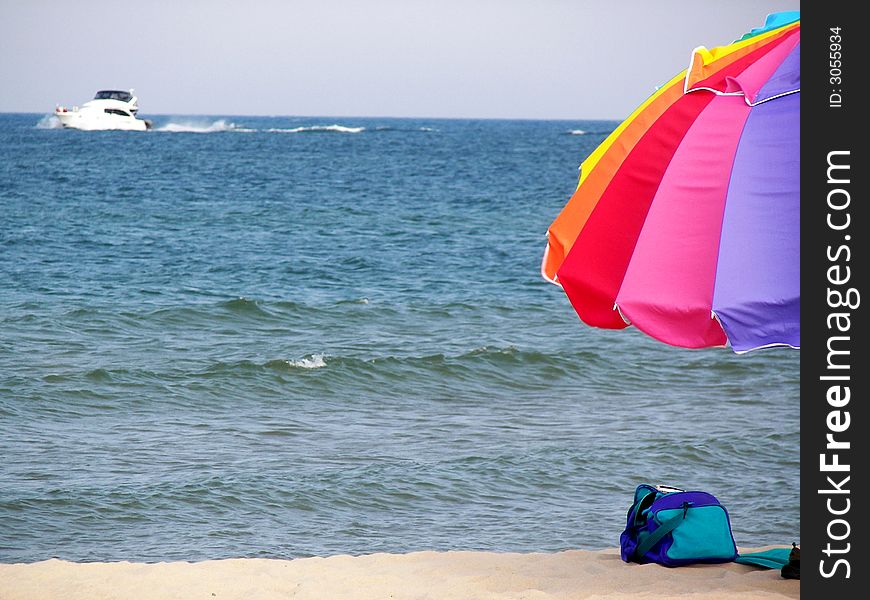 Colorful umbrella on the beach with a power boat on the lake. Colorful umbrella on the beach with a power boat on the lake.