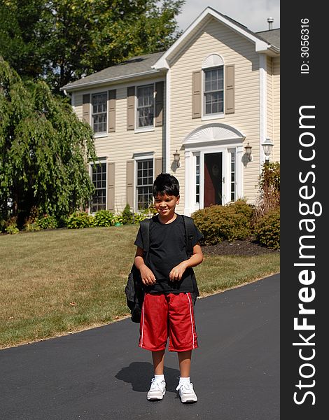 Elementary boy waiting for the school bus in front of his house.