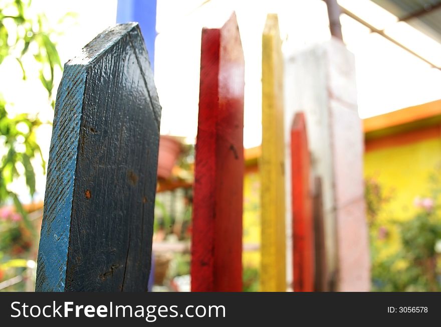 Fence painted with primary colors on a garden, shallow DoF. Fence painted with primary colors on a garden, shallow DoF