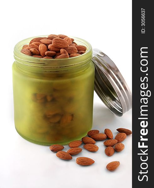 A green jar full of almonds over white background. A green jar full of almonds over white background