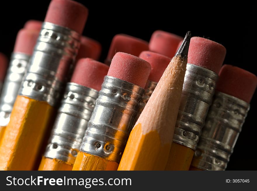 Macro shot of yellow pencils all erasers visible except one sharpened pencil, copy space to the left,