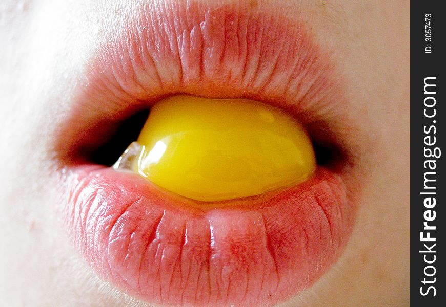 Girl' lips holding a yolk. Girl' lips holding a yolk