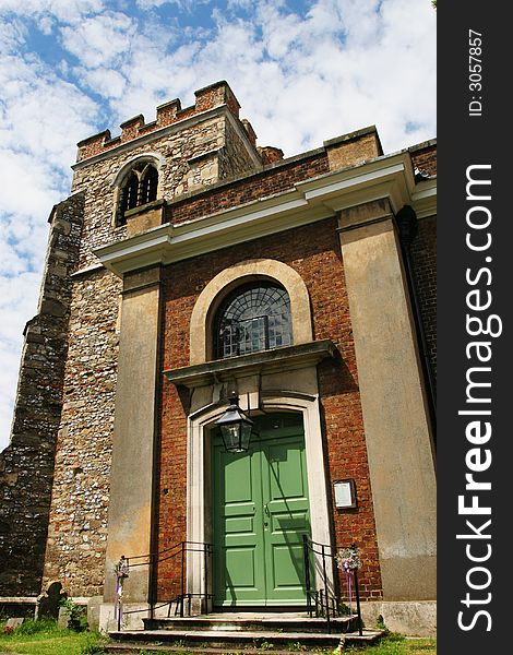 English church door and tower against blue sky and white cloud