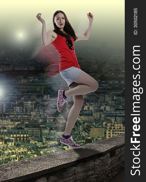 Youthful woman in motion balancing on the edge of high building balcony over the big city. Girl is in risk of falling down. City view from above background. Youthful woman in motion balancing on the edge of high building balcony over the big city. Girl is in risk of falling down. City view from above background.