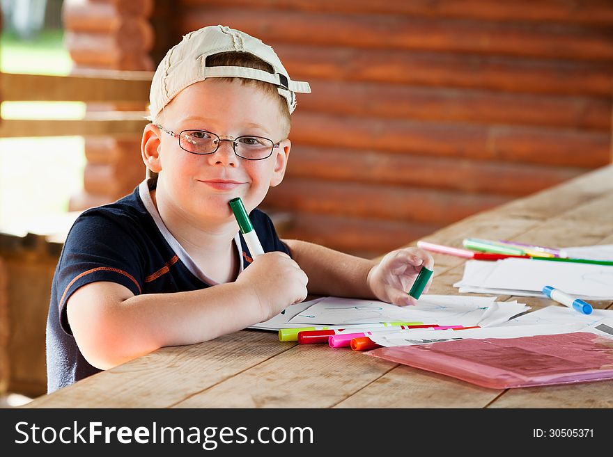 Cute boy drawing in wooden gazebo outdoors