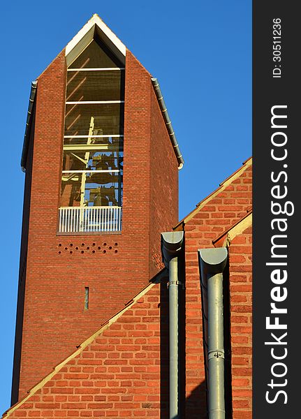 Two zink gutters are seen in front of a red brick wall and tower of a modern church - Aarhus, Denmark. Two zink gutters are seen in front of a red brick wall and tower of a modern church - Aarhus, Denmark