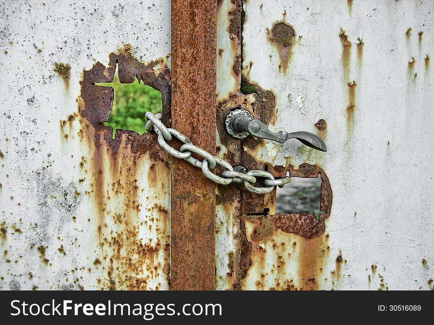 Old and rusty gate locked by chains close up