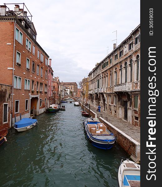 Venice - a view of a small canal with boats and the town street