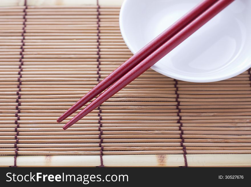 Two chopsticks next to a red and white bowl