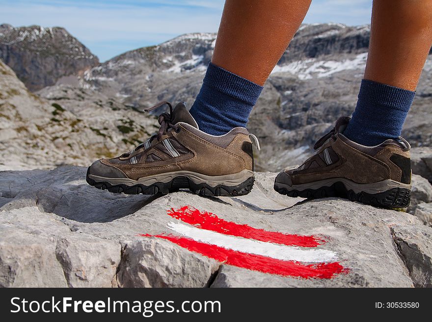 Feet of hiking woman in mountains and marked path. Feet of hiking woman in mountains and marked path