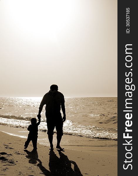 Dad and child on the beach at at sunset. Black and white photo.