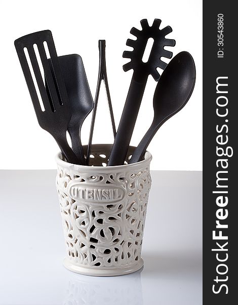 Kitchen utensils in container on white and gray background