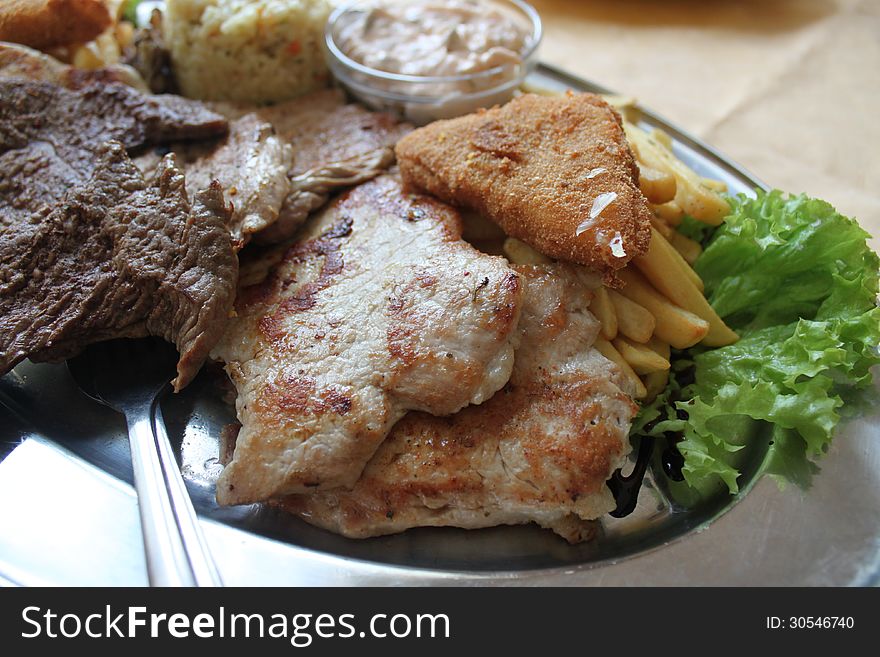 Roast pork and beef with fries and salad. Roast pork and beef with fries and salad