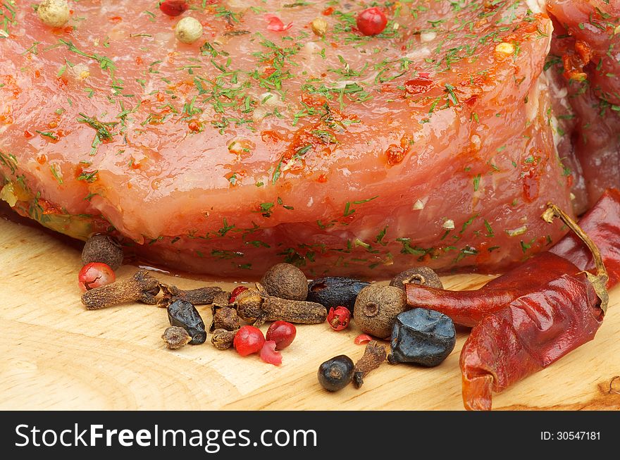 Marinated Raw Pork with Herbs, Dill and Spices closeup on Wooden Cutting Board