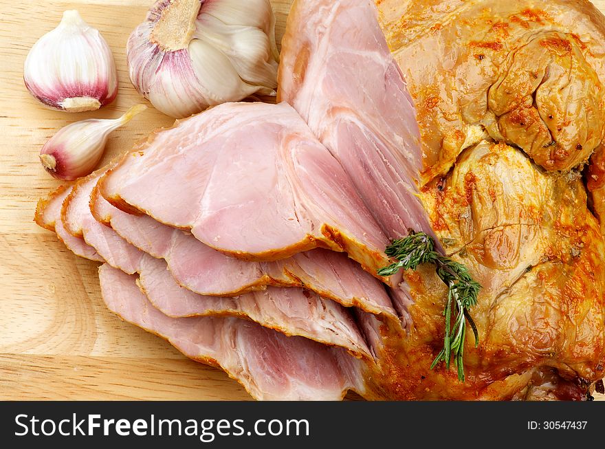 Slices of Delicious Roasted Pork Knuckle Glazed with Spices and Garlic closeup on Cutting Board