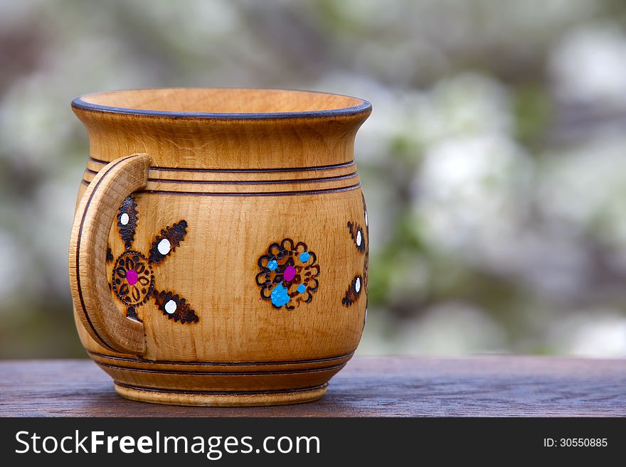 Wooden mug with an ornament on a soft background