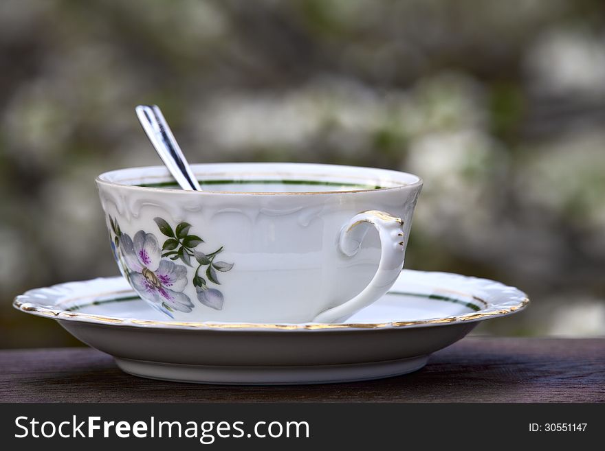 Teacup with saucer and spoon on a soft background