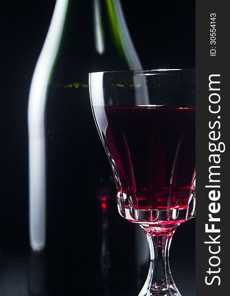 Bottle and glass with red wine on a black background