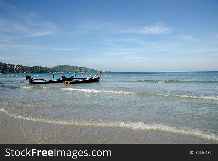 Clean tropical beach with boat and blue sky