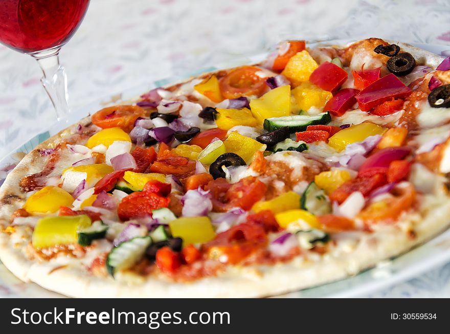 Vegetable pizza served with a glass of wine.