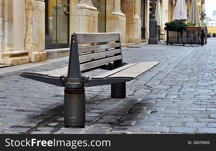 An empty sitting space, next to shops, on a stone paved alley. An empty sitting space, next to shops, on a stone paved alley