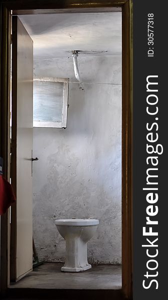 An old toilet that is framed within its door entrance