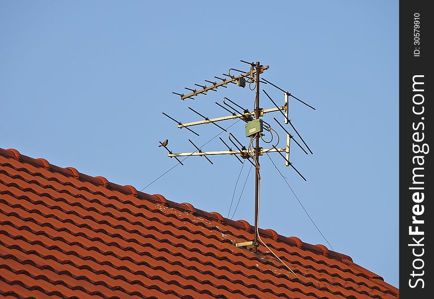 Receiver antenna on red roof in sunlight. Receiver antenna on red roof in sunlight