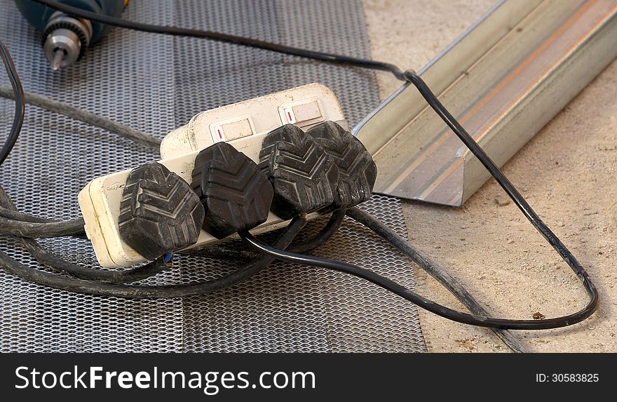 Electrical multi-extender plug being used on construction site with power tool in background. Electrical multi-extender plug being used on construction site with power tool in background