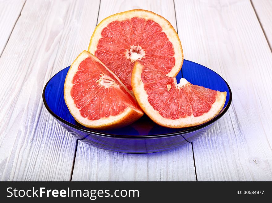 Grapefruit in a blue plate on a light wooden background