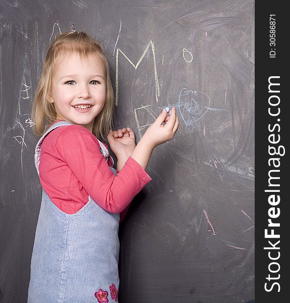 Portrait Of Little Cute Girl Near Blackboard