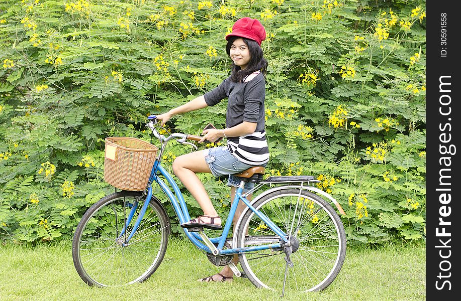 Portrait of pretty young woman with bicycle in a park smiling - Outdoor
