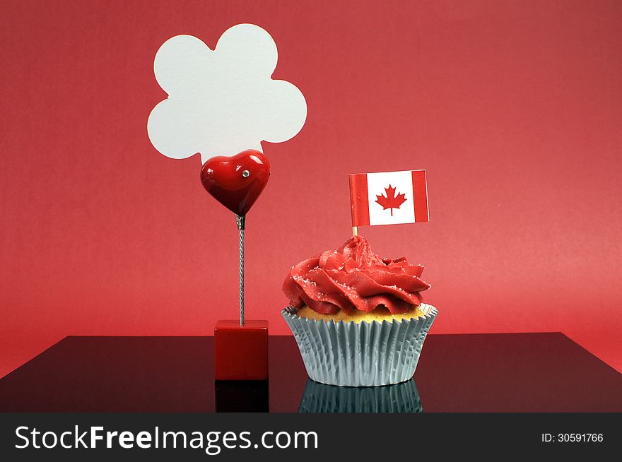 Red and white theme Canadian cupcake with maple leaf flag and sign with Happy Canada Day, Vive Le Canada, or copy space for your text here.