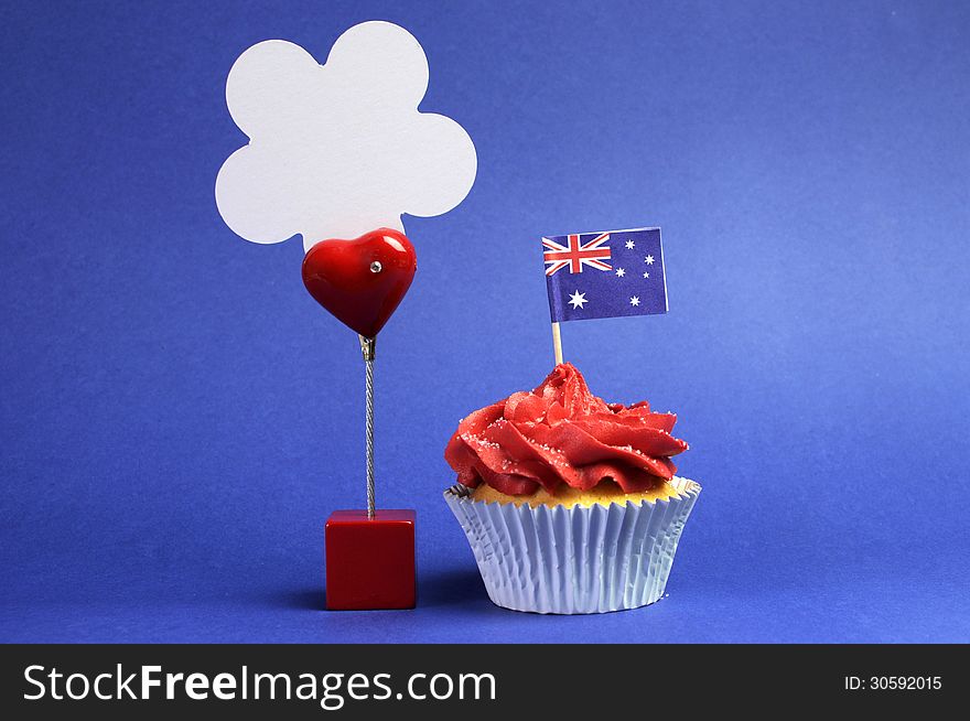 Australian theme red, white and blue cupcake with national flag, and sign for your text here, for Australia Day, Anzac Day or national holiday against a blue background. Australian theme red, white and blue cupcake with national flag, and sign for your text here, for Australia Day, Anzac Day or national holiday against a blue background.