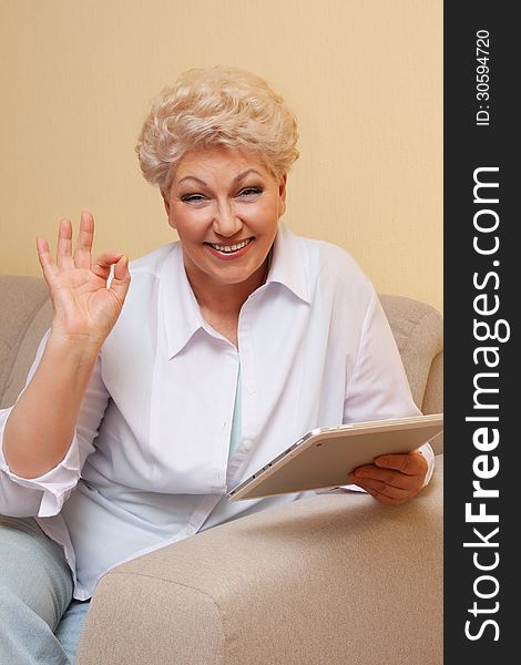 Senior woman sitting on sofa smiling with laptop and show OK. Senior woman sitting on sofa smiling with laptop and show OK