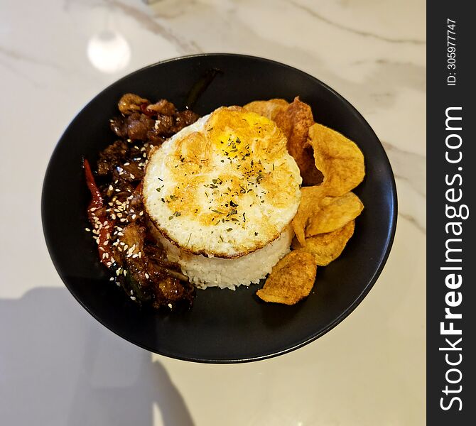 beef blackpepper rice bowl dish with fried egg and fried potatoes